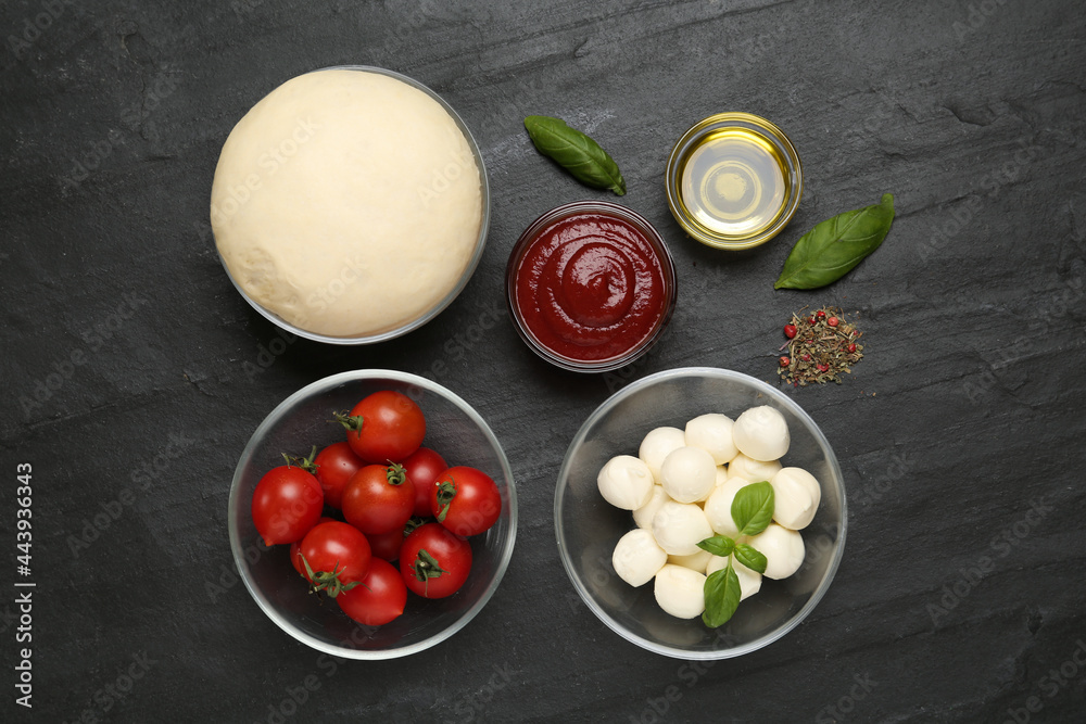 Raw dough and other ingredients for pizza on black table, flat lay Raw dough and other ingredients for pizza on black table, flat lay