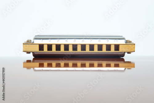 The harmonica lies on a mirrored surface. Classical musical wind instrument. photo