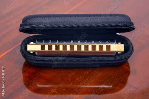 Harmonica in a case on a wooden background. Classical musical wind instrument.