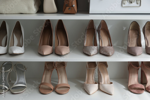 Different stylish women's shoes on shelving unit