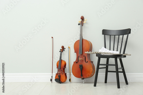 Stringed and wind musical instruments near white wall indoors, space for text