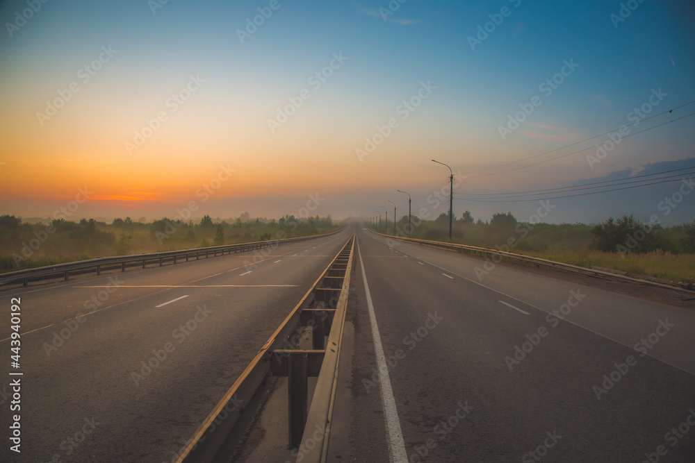 the multi-lane road goes into the distance and gets lost in the predawn haze