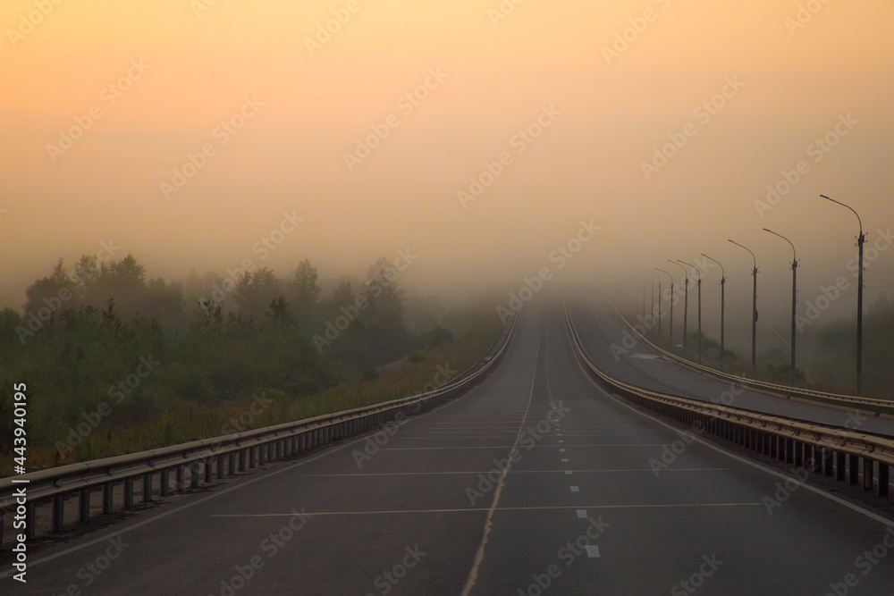 the multi-lane road goes into a thick fog rising over the bridge we pass through the river