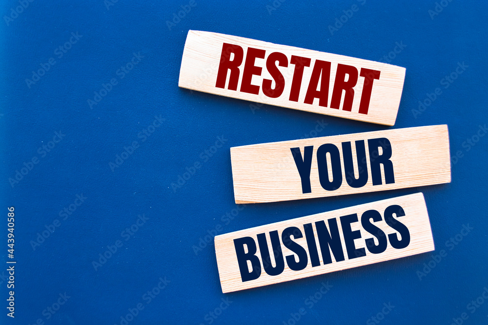 Wooden blocks form the words 'restart your business' on blue background. Copy space. Business concept.