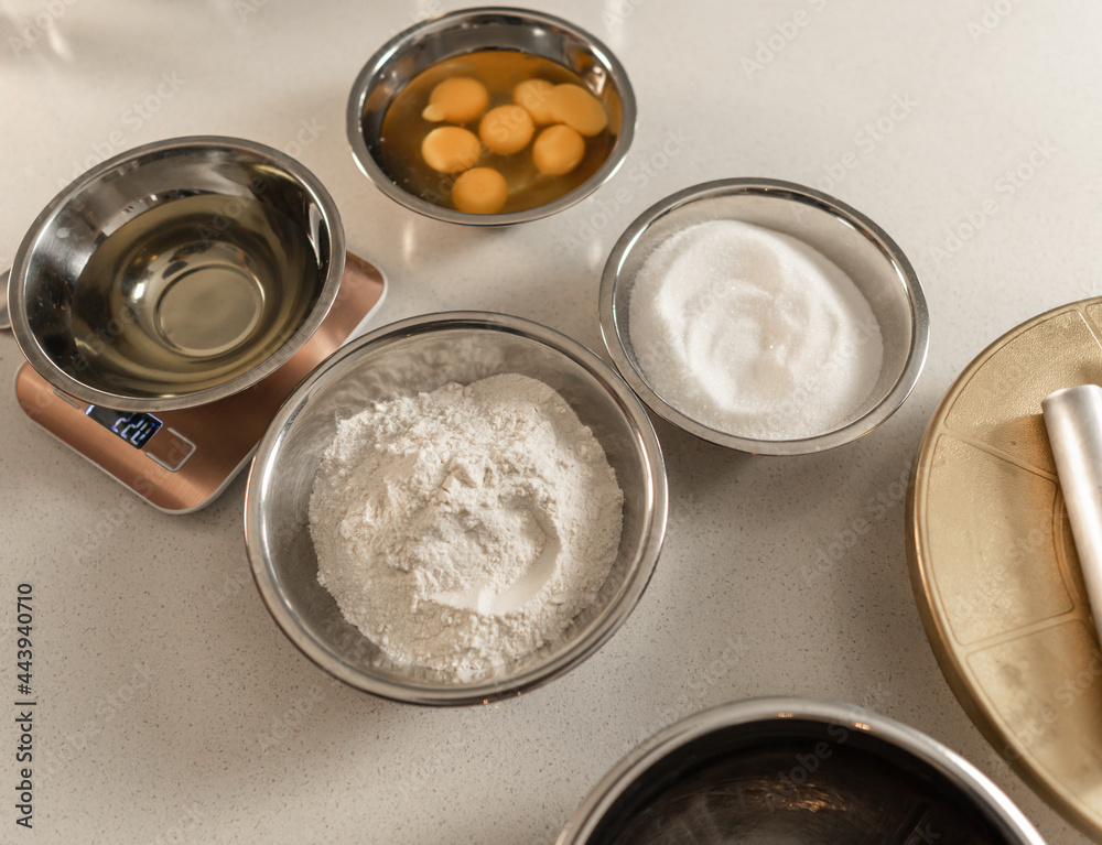 general view of a table with metal bowls with eggs, flour, sugar and more baking ingredients general view of a table with metal bowls with eggs, flour, sugar and more baking ingredients
