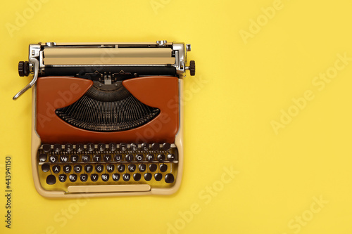 Vintage typewriter on yellow background, top view. Space for text