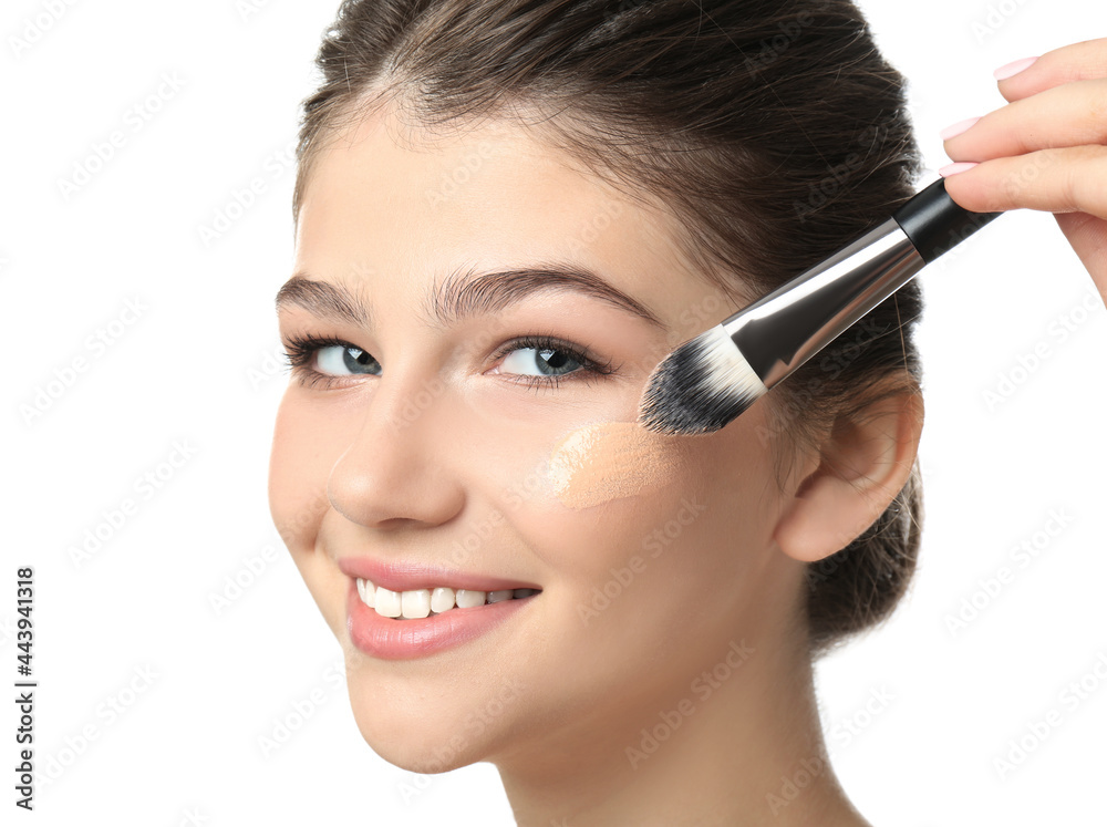 Beautiful girl applying foundation with brush on white background. Face contouring