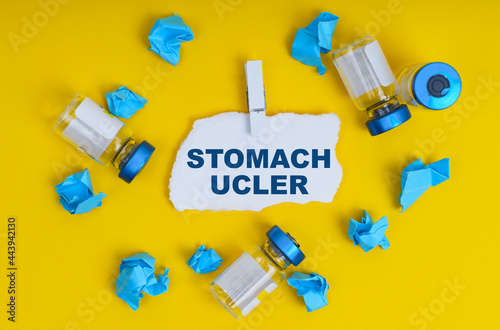 On a yellow background are ampoules, blue crumpled paper and paper with the inscription - STOMACH UCLER photo