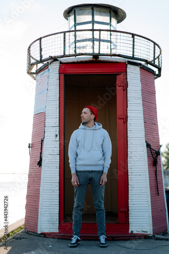 Male tourist at old lighthouse building. Millennial hipster traveler alone recreating meditating at light house. Guy in casual wear travel alone for recreation hiking to landmarks. Lifestyle concept