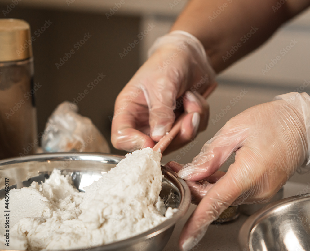 Hands with transparent gloves handling butter cream in a metal bowl. Hands with transparent gloves handling butter cream in a metal bowl.