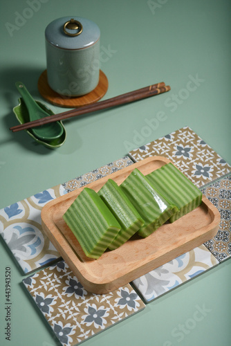 local traditional nyonya green colour pandan kueh desert and chinese yellow steam cup cake in green display background and old tile design asian halal dessert menu photo