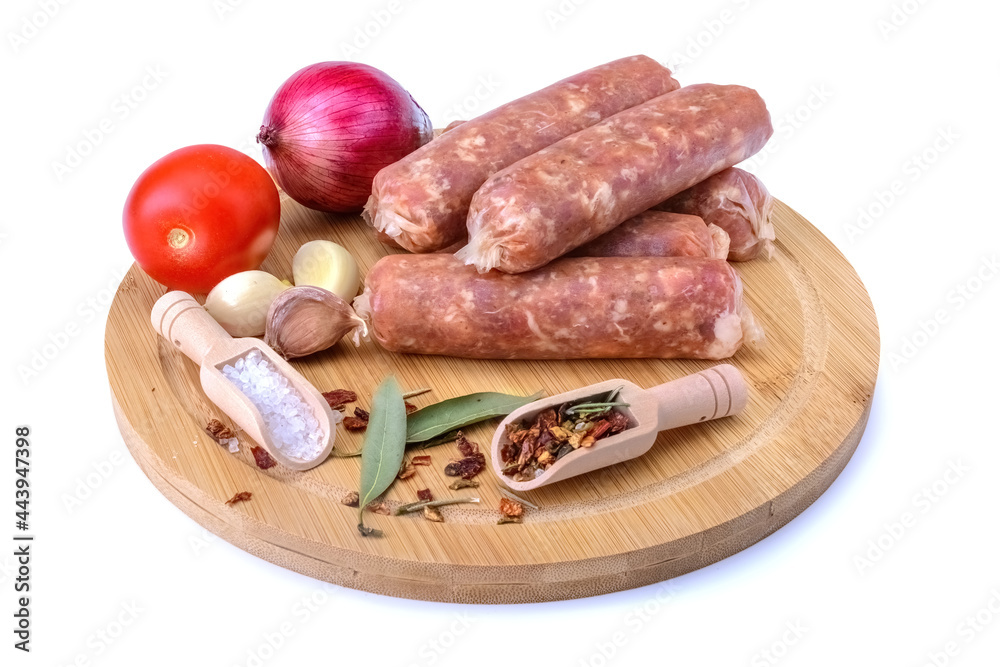 Raw homemade pork sausages laid out with spices on a round wooden board, isolated on a white background.Selective focus.top view. Raw homemade pork sausages laid out with spices on a round wooden board, isolated on a white background.Selective focus.top view.