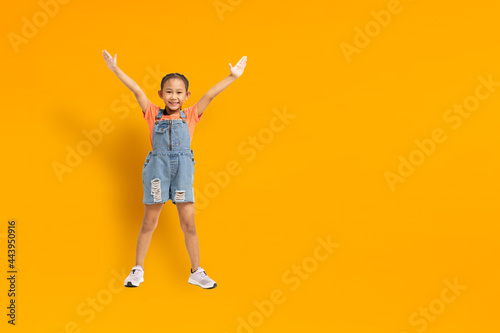 Funny asian child girl on yellow background