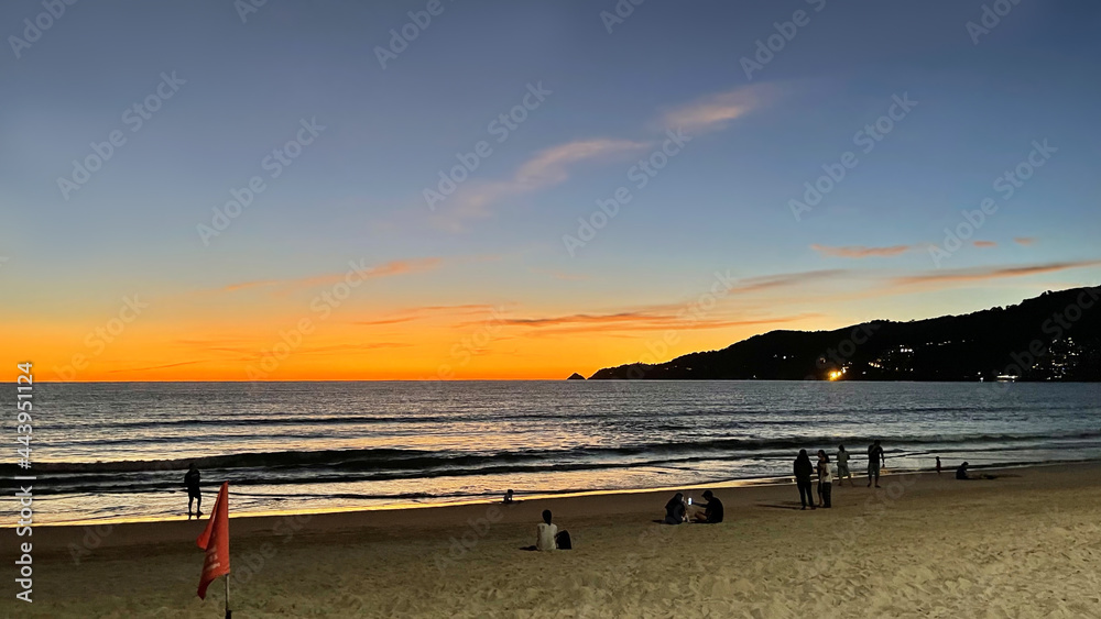 Tourist campaign to attract vaccinated tourists without quarantine Phuket Sandbox. Beautiful nature of Thailand. Patong beach at sunset. Silhouettes of people resting on sand. Monsoon season. Sundown