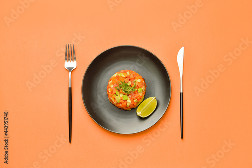 Plate with tasty tartare salad and lime on color background