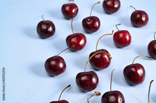 Ripe red cherries with leaves on blue background.