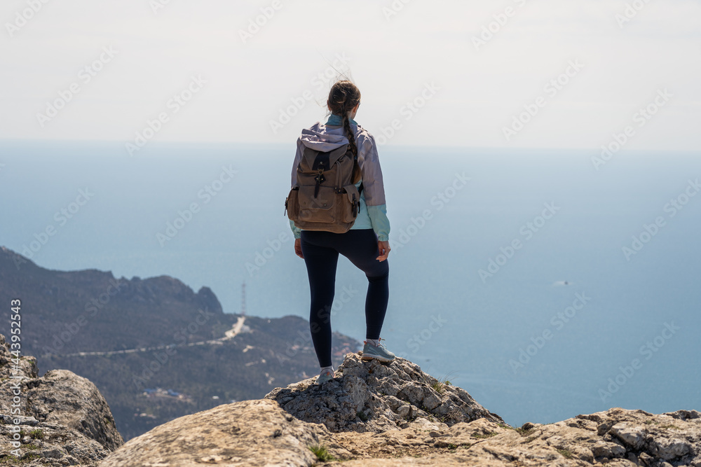 A traveler with a backpack admires the sea view from a great height. The concept of travel and outdoor recreation. Far from the big city.