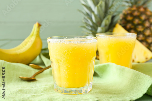 Glasses of tasty pineapple smoothie on color wooden background, closeup