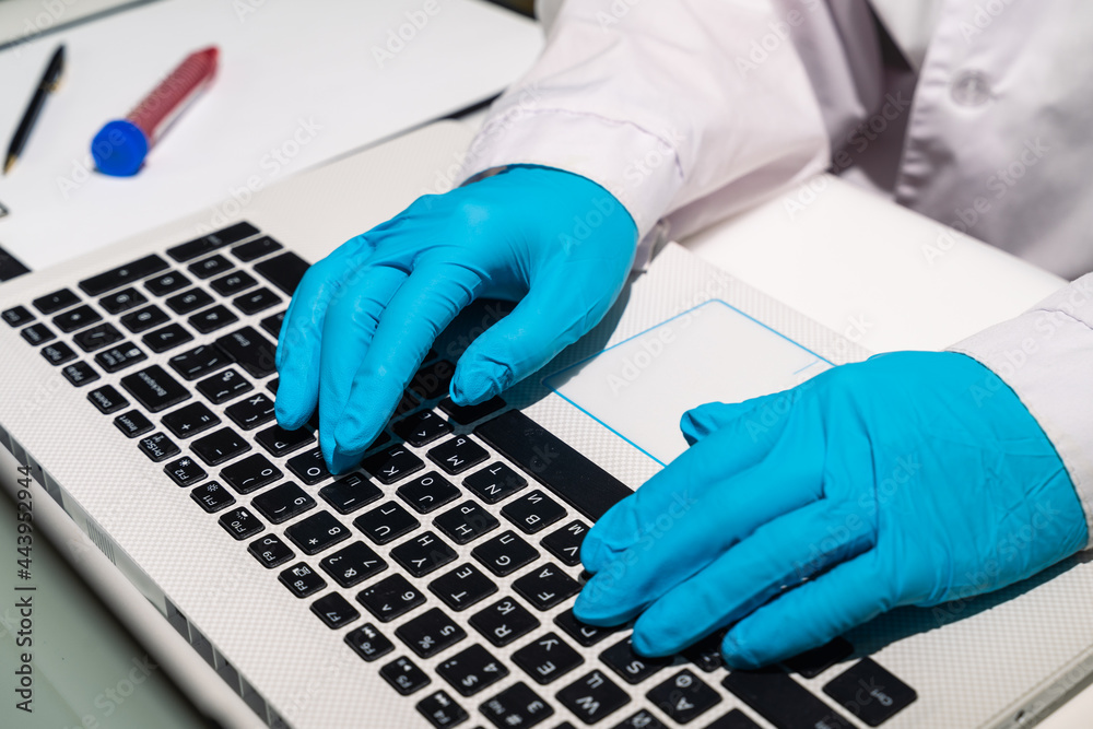 The doctor's hands in medical gloves lie on the keyboard. The doctor is typing text on the computer. A medical worker writes out a sick leave electronically. Close-up The doctor's hands in medical gloves lie on the keyboard. The doctor is typing text on the computer. A medical worker writes out a sick leave electronically. Close-up