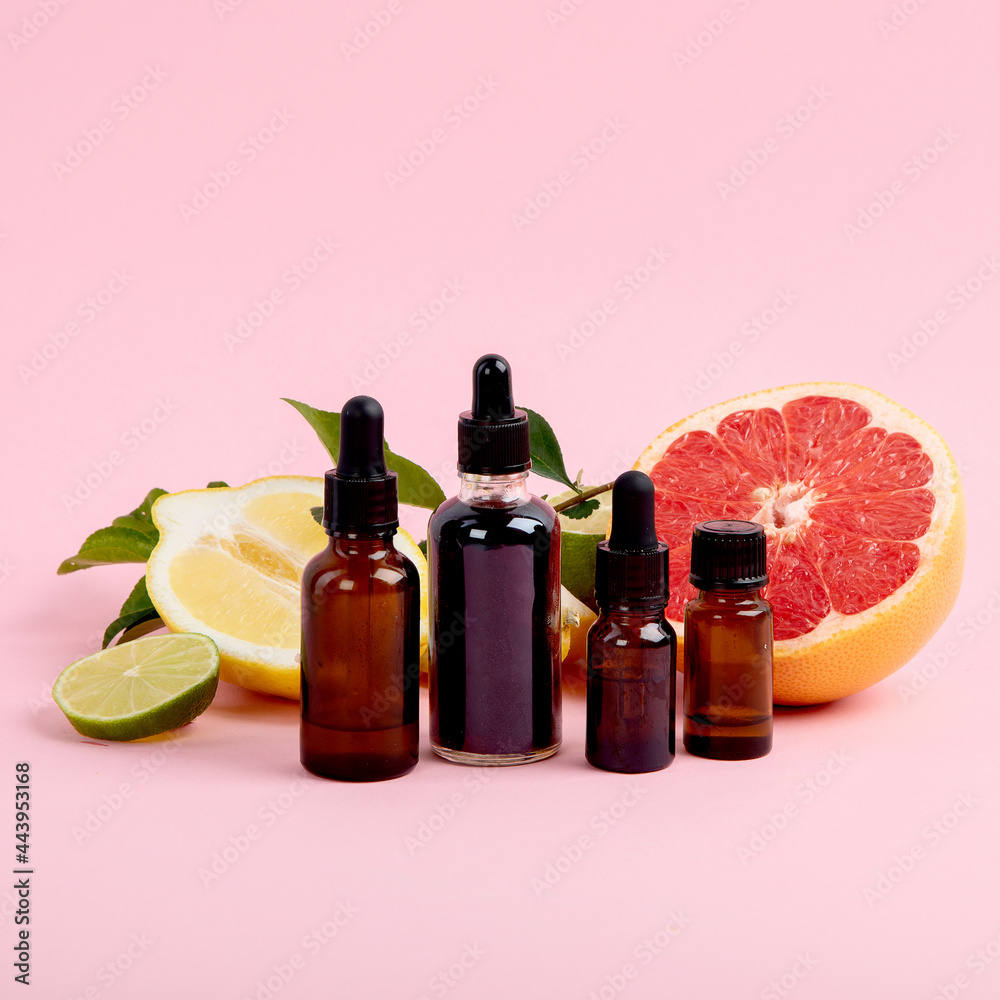 Bottles of essential aroma oils with citrus on pink background. Bottles of essential aroma oils with citrus on pink background.
