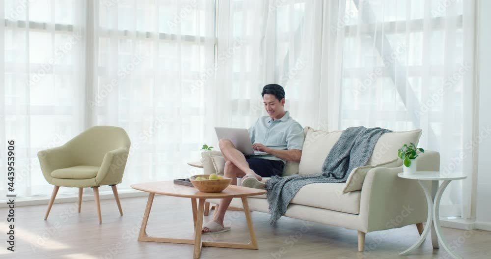 Happy young man using laptop in living room,4K Happy young man using laptop in living room,4K