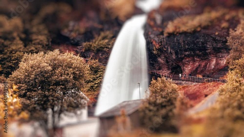 Tilt-shift video of the Steinsdalsfossen waterfall in autumn. People walking on the walkway under the waterfall. photo
