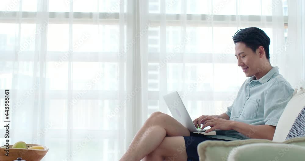 Happy young man using laptop in living room,4K Happy young man using laptop in living room,4K
