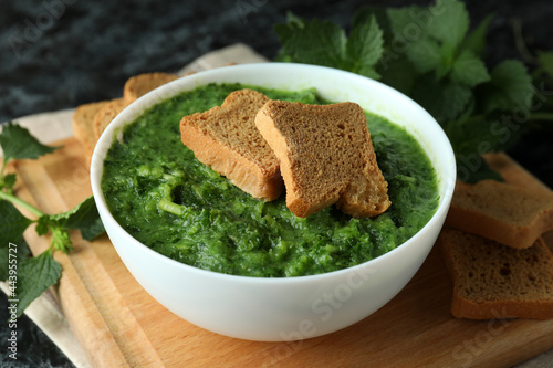 Concept of healthy food with nettle soup on black smokey table