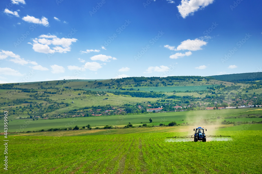 Farming tractor plowing and spraying on field Farming tractor plowing and spraying on field
