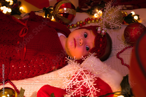 a cute girl in a red outfit on a white blanket on Christmas Eve.