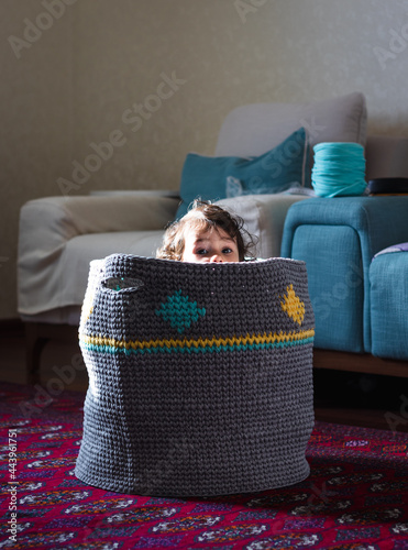 a cute curly girl in a knitted grey basket