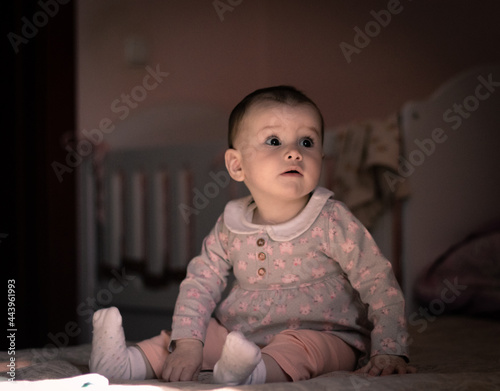 portrait of a cute little girl sitting on the bed in her room.