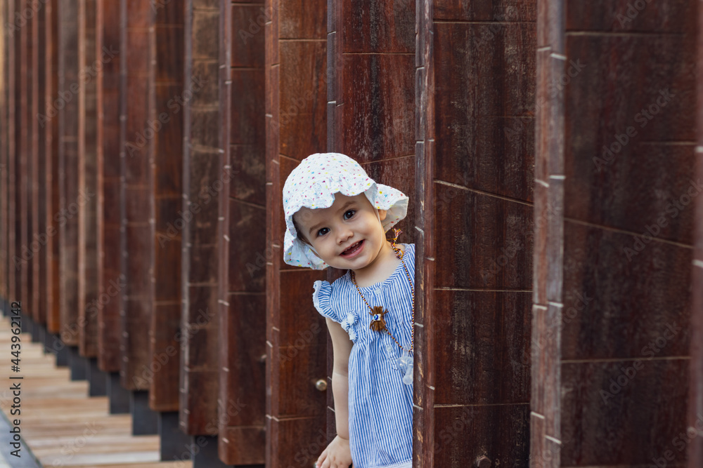 portrait of a cute little girl in lamer Dubai peeking out of the wooden beams