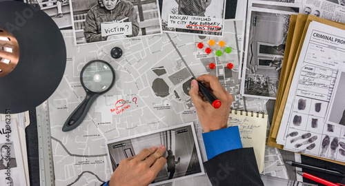 The police detective draws a track on the map of the city and places a tag.