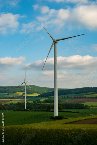 Wind power plant consisting of two wind turbines in an agricultural landscape, with blue sky and clouds in background, Weserbergland, Lower Saxony, Germany.