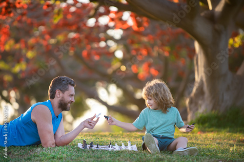 Happy family outdoor. Father and son playing chess in autumn garden.