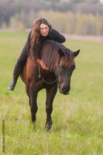 a woman with loose hair strokes her horse's mane