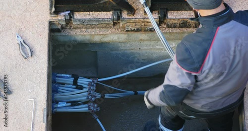 Worker made a break-in with an electric demolition hammer in the reinforced concrete shaft of the fiber optic cable line. Open triangular cast iron manhole covers