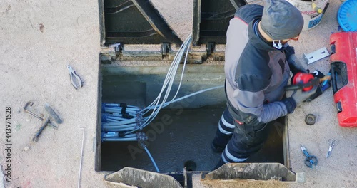 Worker made a break-in with an electric demolition hammer in the reinforced concrete shaft of the fiber optic cable line. Open triangular cast iron manhole covers