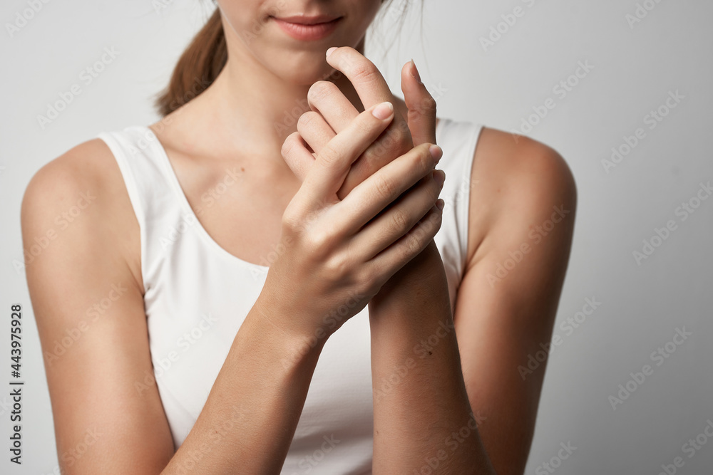 woman in white t-shirt holds hand health problems chronic pain woman in white t-shirt holds hand health problems chronic pain