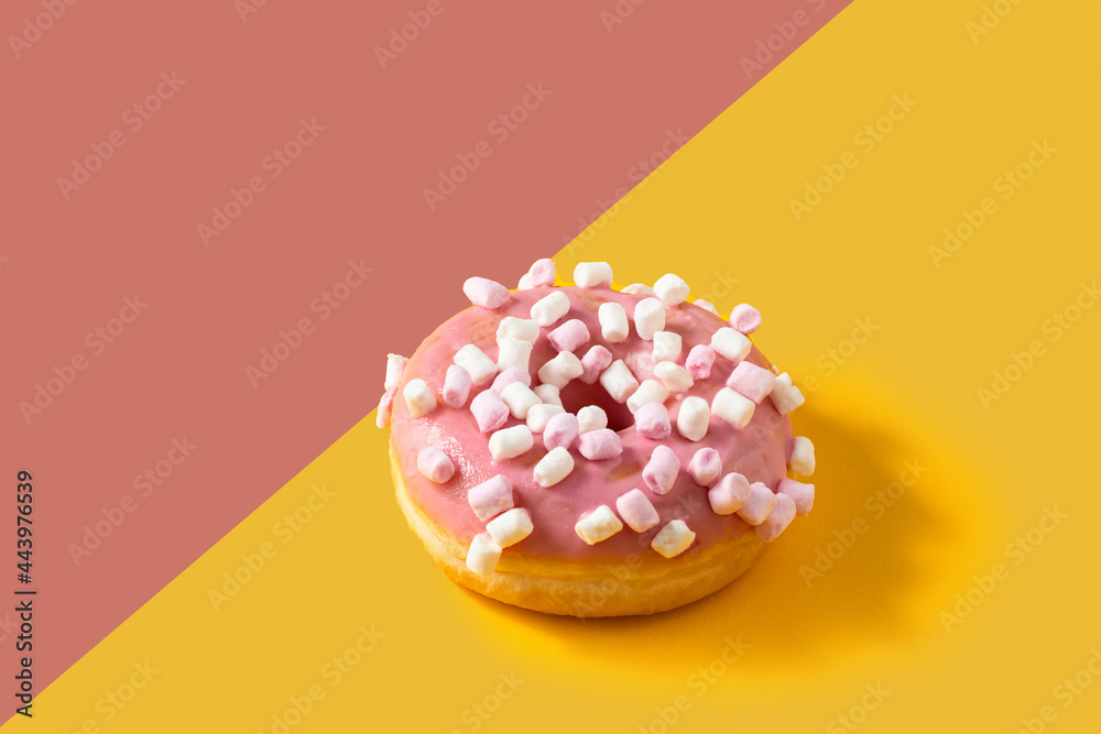 Donut with pink frosted and marshmallow topping on two colour background Donut with pink frosted and marshmallow topping on two colour background