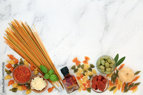 Italian low cholesterol health food ingredients for a healthy diet with tricolour pasta, vegetables, passata, olive oil, parmesan. High in fibre, protein, omega 3 and antioxidants. On marble top view.