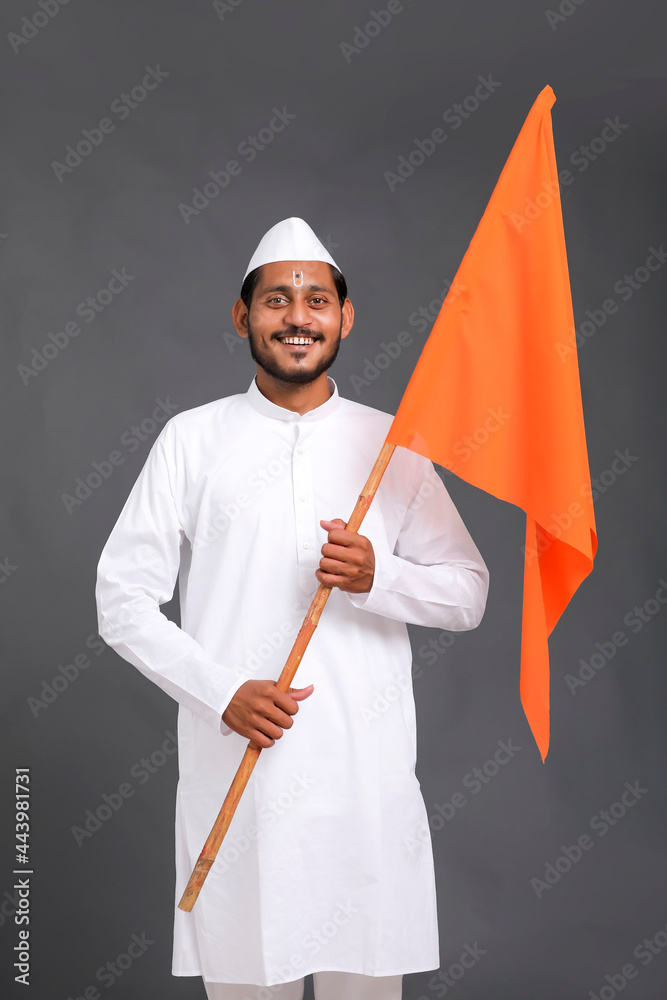 Young indian man (pilgrim) in traditional wear and waving religious flag. Young indian man (pilgrim) in traditional wear and waving religious flag.