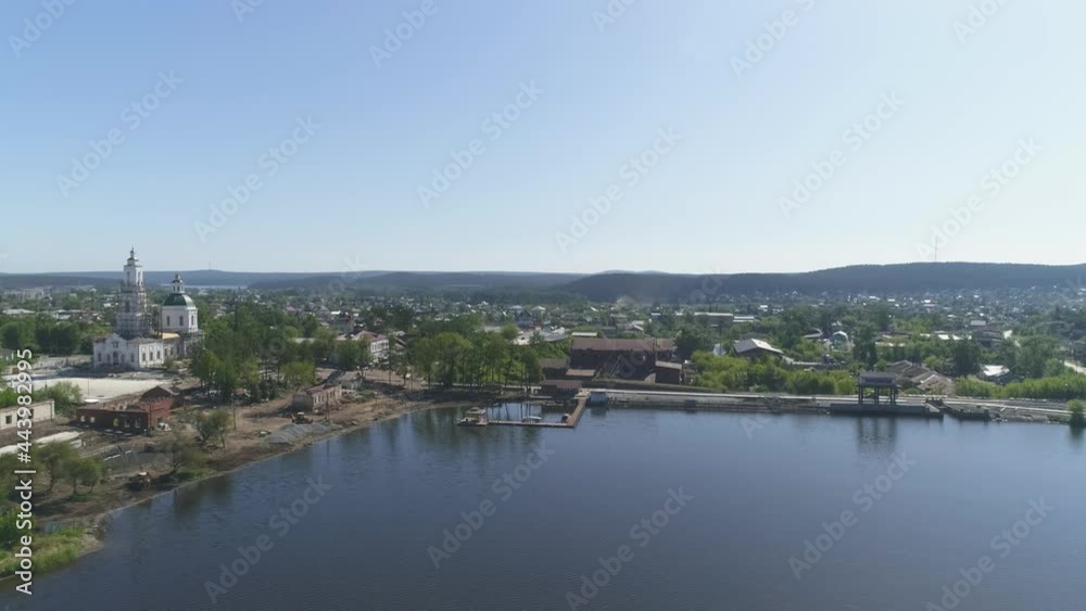 Aerial view of Construction of a embankment in the provincial town. Reconstruction of the old church and old houses. Next to the pond is an old factory. Trees and building materials on the shore. Summ Aerial view of Construction of a embankment in the provincial town. Reconstruction of the old church and old houses. Next to the pond is an old factory. Trees and building materials on the shore. Summ