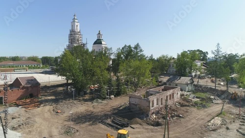 Aerial view of Construction of a embankment and pier with a gazebo on the city pond. Reconstruction of the old church and old houses. Trees and building materials on the shore. Summer sunny day
 photo