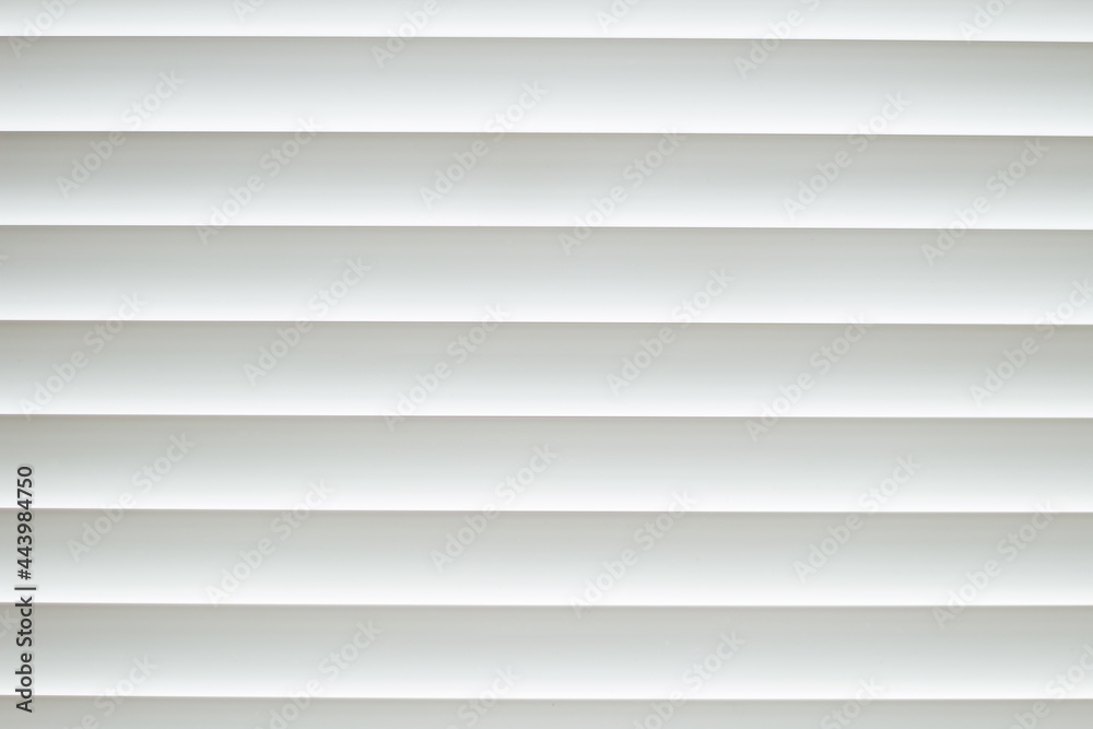 Fototapeta premium Frontal close-up view of white office shutters made of metal. The curtains cover the window. The strips are horizontally parallel to each other. Texture, background and copy space.