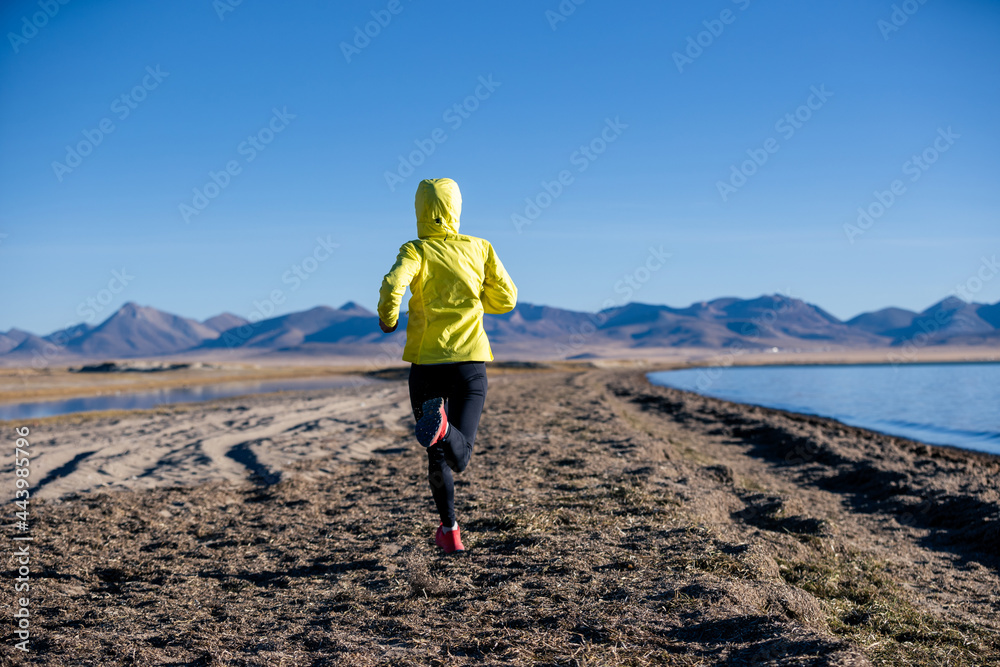 Woman trail runner cross country running on winter high altitude lakeside