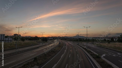 Beautiful day to night timelapse of busy highway with purple sky colors and traffic light trails during sunset photo