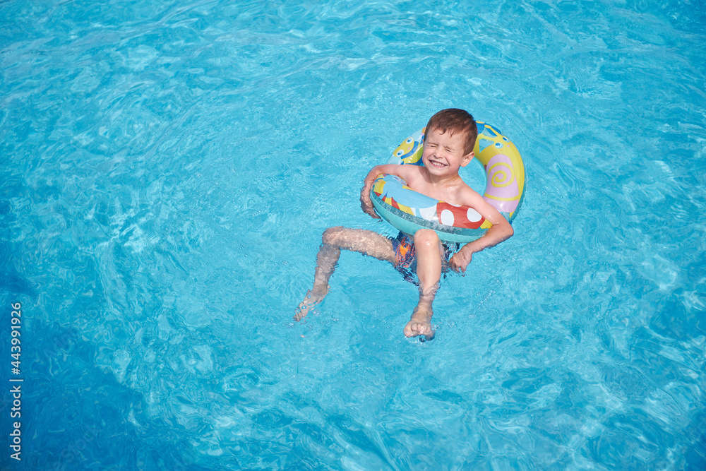 Happy boy swimming in an outdoor swimming pool in summer using swimming circle