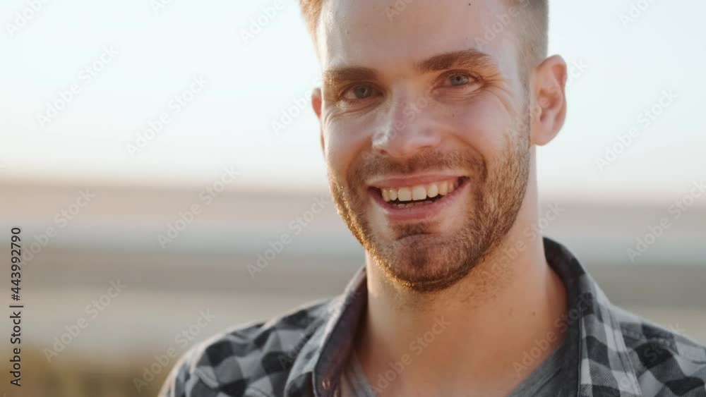A handsome man is posing to the camera standing outdoors at summer A handsome man is posing to the camera standing outdoors at summer